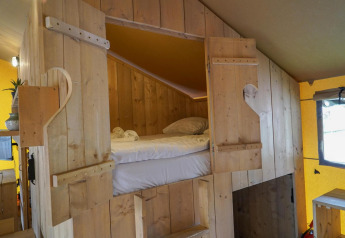 Cozy sleeping area inside a Glampingtent at Het Amsterdamse Bos in the Netherlands with wood walls.