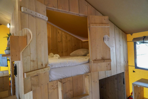 Zona notte accogliente in una Glampingtent presso Het Amsterdamse Bos nei Paesi Bassi con pareti in legno.