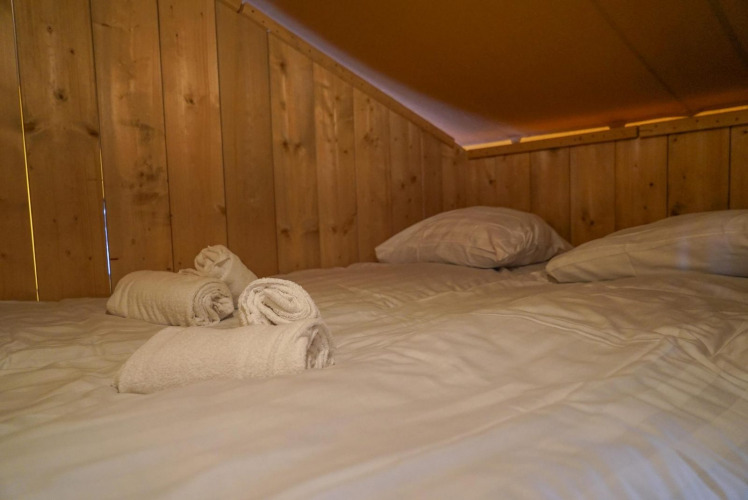 Cozy bed with white towels and pillows inside the Glampingtent at Het Amsterdamse Bos in the Netherlands.