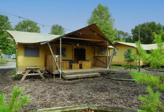 Tente glamping au Het Amsterdamse Bos, Pays-Bas, avec terrasse, meubles en bois et verdure.