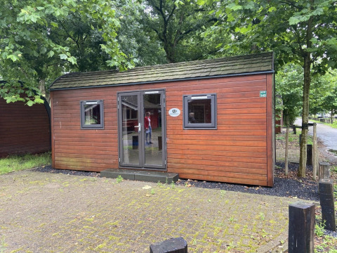 Foto de una pequeña casa de madera llamada Pod, rodeada de árboles y situada en una zona tranquila.