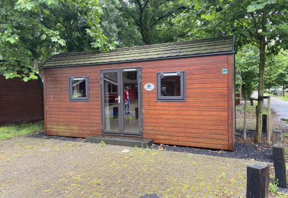Foto de una pequeña casa de madera llamada Pod, rodeada de árboles y situada en una zona tranquila.