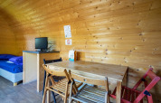 Interior de una pequeña casa de madera con mesa de comedor, sillas, cama y TV, Pod en Het Amsterdamse Bos.