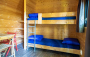 Intérieur en bois d'une tiny house Pod à Het Amsterdamse Bos avec lits superposés, linge bleu et table.
