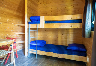 Intérieur en bois d'une tiny house Pod à Het Amsterdamse Bos avec lits superposés, linge bleu et table.