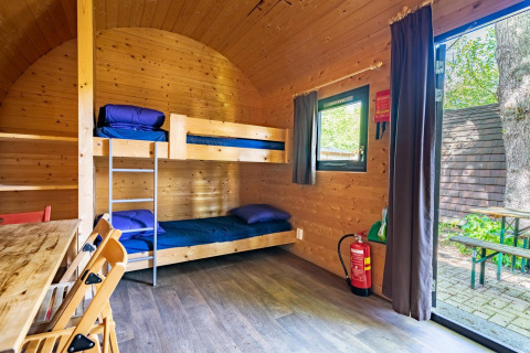 Interior de una pequeña casa de madera tipo Pod con literas y mesa, ubicada en Het Amsterdamse Bos, Países Bajos.