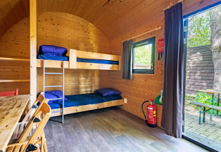 Interior de una pequeña casa de madera tipo Pod con literas y mesa, ubicada en Het Amsterdamse Bos, Países Bajos.