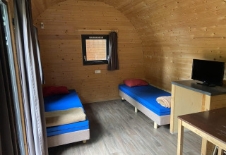 Interior de una pequeña casa Pod en Het Amsterdamse Bos, Países Bajos, con dos camas individuales y televisor.
