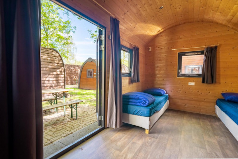 Vista interior de una pequeña casa Pod con paredes de madera y dos camas en Het Amsterdamse Bos, Países Bajos.