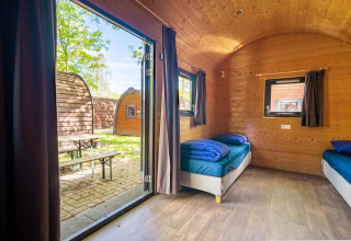Vista interior de una pequeña casa Pod con paredes de madera y dos camas en Het Amsterdamse Bos, Países Bajos.