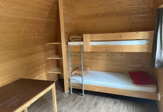 Interior de una pequeña casa de madera con litera, estanterías y escritorio en Het Amsterdamse Bos, Países Bajos.