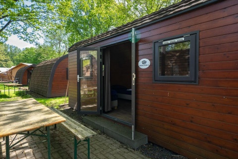 Exterior de la tiny house Pod en Het Amsterdamse Bos, Países Bajos, con naturaleza y mesa de picnic.