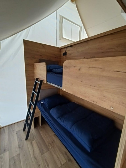 Lits superposés en bois avec literie bleu marine dans une chambre du lodge Papillio à Poort van Maastricht.