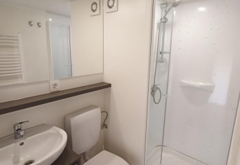 Modern badkamerinterieur in een glampingverblijf, met douche, toilet, wastafel en houten vloer.