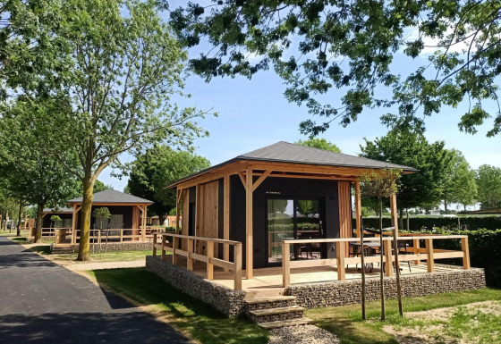 Moderne tiny house met houten veranda, gelegen in een groene en zonnige omgeving om te relaxen.