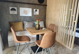Modern eetgedeelte in een tiny house met houten tafel, bruine stoelen en wanddecoratie in Maastricht.