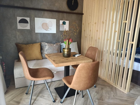 Moderne spiseområde i et tiny house med træbord, brune stole, pyntepuder og vægkunst i Maastricht.