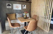 Coin repas moderne dans une tiny house avec table en bois, chaises brunes et décor mural à Maastricht.