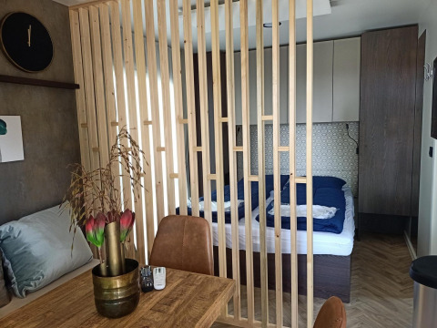 Binnenkant van een Tiny House bij Poort van Maastricht, met houten afscheiding en zicht op bed en tafel.
