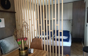 Interior de una Tiny House en Poort van Maastricht, con separador de madera, mesa y zona de dormitorio.