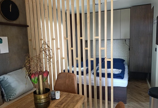 Binnenkant van een Tiny House bij Poort van Maastricht, met houten afscheiding en zicht op bed en tafel.