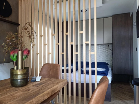 Interior de una tiny house en Poort van Maastricht, Países Bajos, con dormitorio separado por listones de madera.