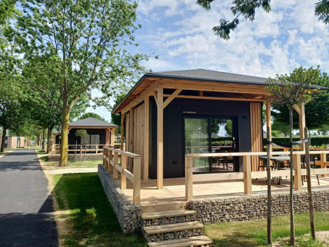 Tiny house bij Poort van Maastricht, Nederland, met houten terras en omgeven door bomen en groen.