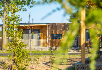 Zicht op een moderne houten lodge bij Palisade, omgeven door bomen en groen op een zonnige dag buiten.