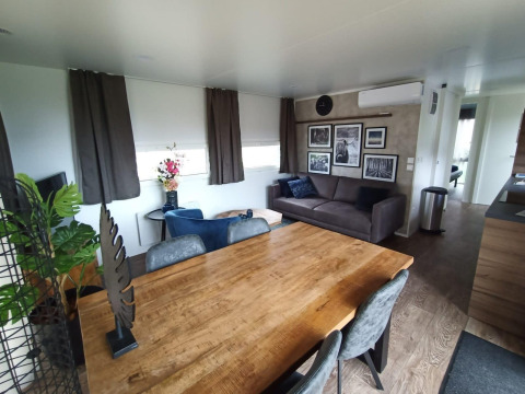 Modernes Wohnzimmer mit Holztisch, grauem Sofa und Wandkunst in der Palisade Lodge bei Poort van Maastricht.