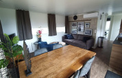 Sala moderna con mesa de madera, sofá gris y arte en la pared en Palisade Lodge en Poort van Maastricht, Países Bajos.