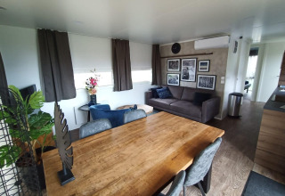 Soggiorno moderno con tavolo in legno, divano grigio e quadri al Palisade Lodge di Poort van Maastricht, Paesi Bassi.