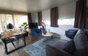 Salón moderno de lodge en Palisade, Poort van Maastricht, Países Bajos, con decoración acogedora y muebles de madera.