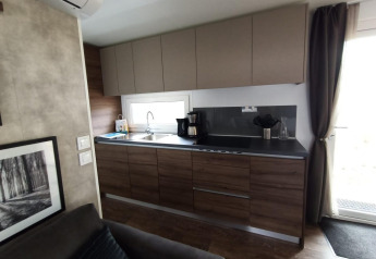 Moderne kitchenette met houten kasten, koffiezet en raam in Palisade lodge te Poort van Maastricht.