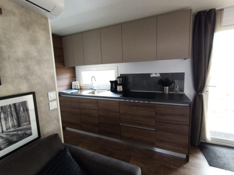 Cocina moderna con armarios de madera, cafetera y ventana en Palisade lodge en Poort van Maastricht.