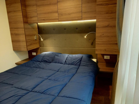 Modernes Schlafzimmer mit blauem Bett, Holzschränken und Wandlampen im Palisade, Poort van Maastricht, Niederlande.