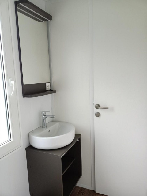 Lavabo moderno con espejo y mueble junto a una puerta blanca en una cabaña de Maastricht, Países Bajos.