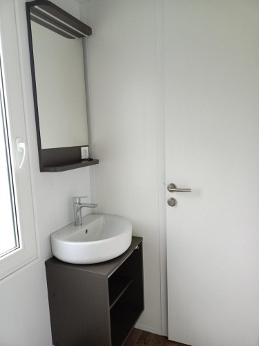 Lavabo moderno con espejo y mueble junto a una puerta blanca en una cabaña de Maastricht, Países Bajos.