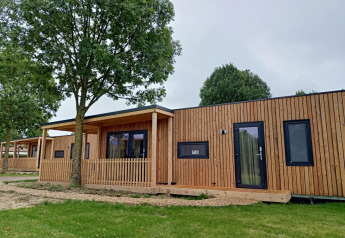 Moderne houten lodge aan Palisade bij Poort van Maastricht in Nederland, omgeven door bomen en gras.