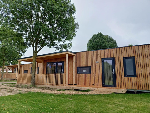 Moderne houten lodge aan Palisade bij Poort van Maastricht in Nederland, omgeven door bomen en gras.