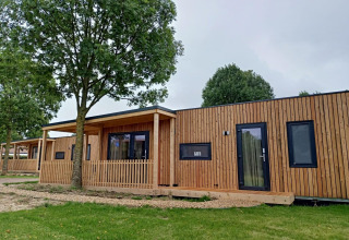 Lodge moderne en bois à Palisade, Poort van Maastricht aux Pays-Bas, entouré d’arbres et de pelouse.