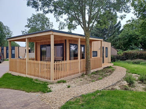 Lodge Palisade avec terrasse en bois à Poort van Maastricht aux Pays-Bas, entouré de verdure et d’allées.