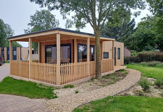 Palisade-lodge met houten terras bij Poort van Maastricht in Nederland, omringd door natuur en wandelpad.