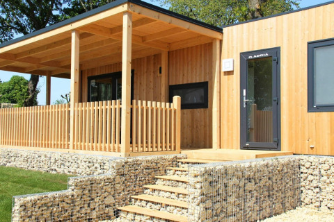 Moderne houten lodge met overdekt terras en stenen muren bij Palisade, Poort van Maastricht, Nederland.