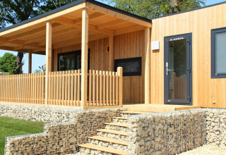 Moderna cabaña de madera con terraza cubierta y muros de piedra en Palisade, Poort van Maastricht, Países Bajos.