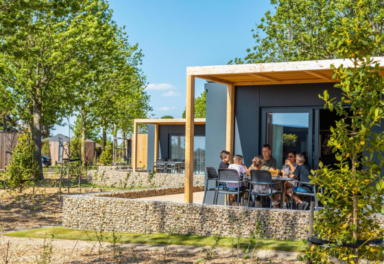 Familia disfrutando al aire libre en la terraza de la Belsano lodge, rodeada de árboles y cabañas modernas.