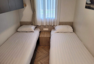 Deux lits simples dans une chambre lumineuse du lodge Belsano, Poort van Maastricht, Pays-Bas, avec fenêtre.