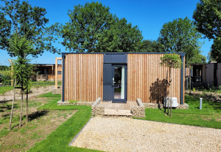 Lodge Belsano à Poort van Maastricht, Pays-Bas, entouré d’arbres et pelouse sous un ciel bleu clair.