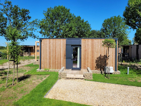 Lodge Belsano à Poort van Maastricht, Pays-Bas, entouré d’arbres et pelouse sous un ciel bleu clair.