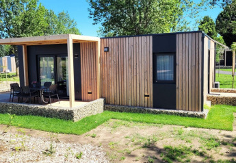 Moderno lodge in legno Belsano al Poort van Maastricht con terrazza, giardino e alberi verdi.