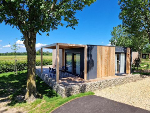 Modern glamping accommodation Domus with wooden facade, outdoor terrace, and seating in natural setting.